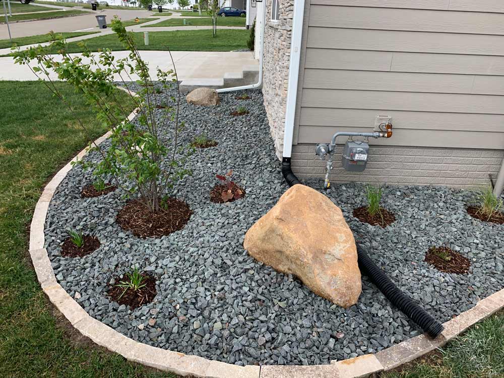wrap-around-flower-bed-with-boulders-plantings